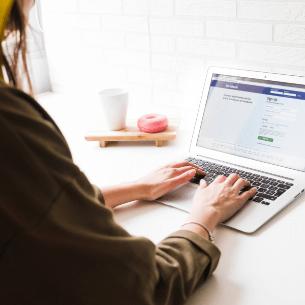 LMB Marketing Facebook on laptop Over-the-shoulder view of a woman using Facebook on her laptop with the screen displaying her social log on page