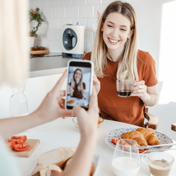 Social media content creator being recorded on a cellphone in a kitchen.